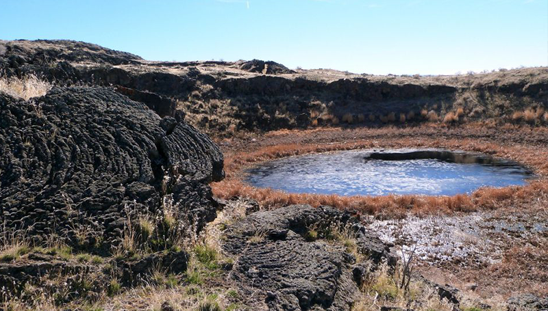 HOT SPRING WITH MOUNTAINS AND BLUE SKY